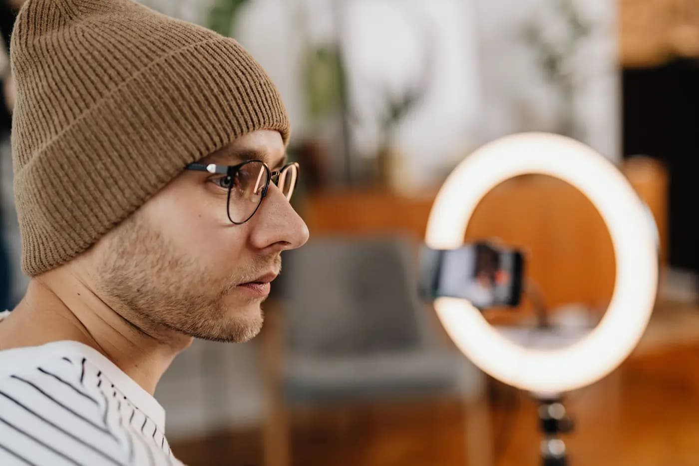 Man in front of a ring light recording a video with a smartphone